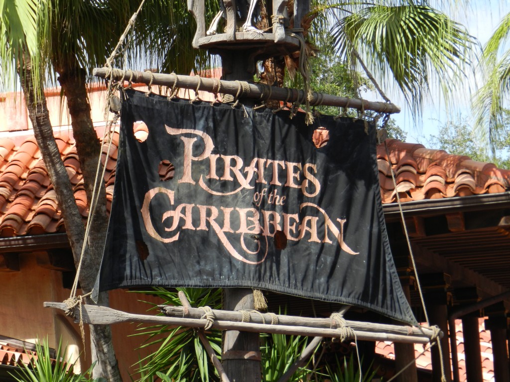 Pirates of the Caribbean black flag with red text at the Magic Kingdom. Keep reading to learn about Magic Kingdom for adults the Disney grown up way. 