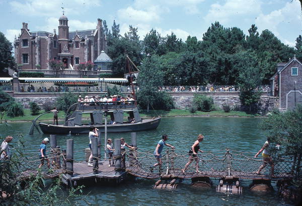 Visitors crossing barrel bridge to Tom Sawyer Island attraction near Haunted Mansion at the Magic Kingdom - Orlando, Florida. Keep reading for Disney World Haunted Mansion secrets and facts.