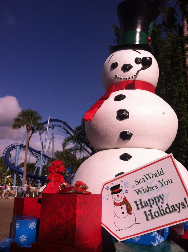 Happy Holidays from SeaWorld Orlando with Cheery Snowman in the Florida Sun with Manta roller coaster in the background.