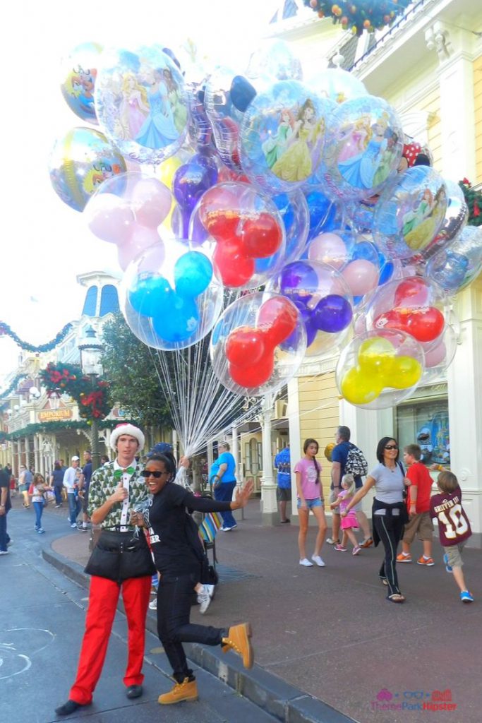 Christmas at Disney Parks with Disney Cast Member Holding Balloons in Magic Kingdom. Keep reading to learn about the best things to do at 2023 Disney World for Christmas.
