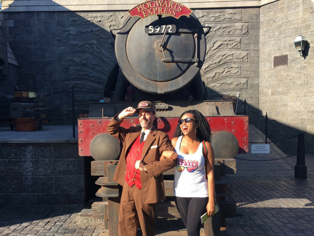 Standing with Hogwarts Express Conductor in front of red train in The Wizarding World of Harry Potter Guide.