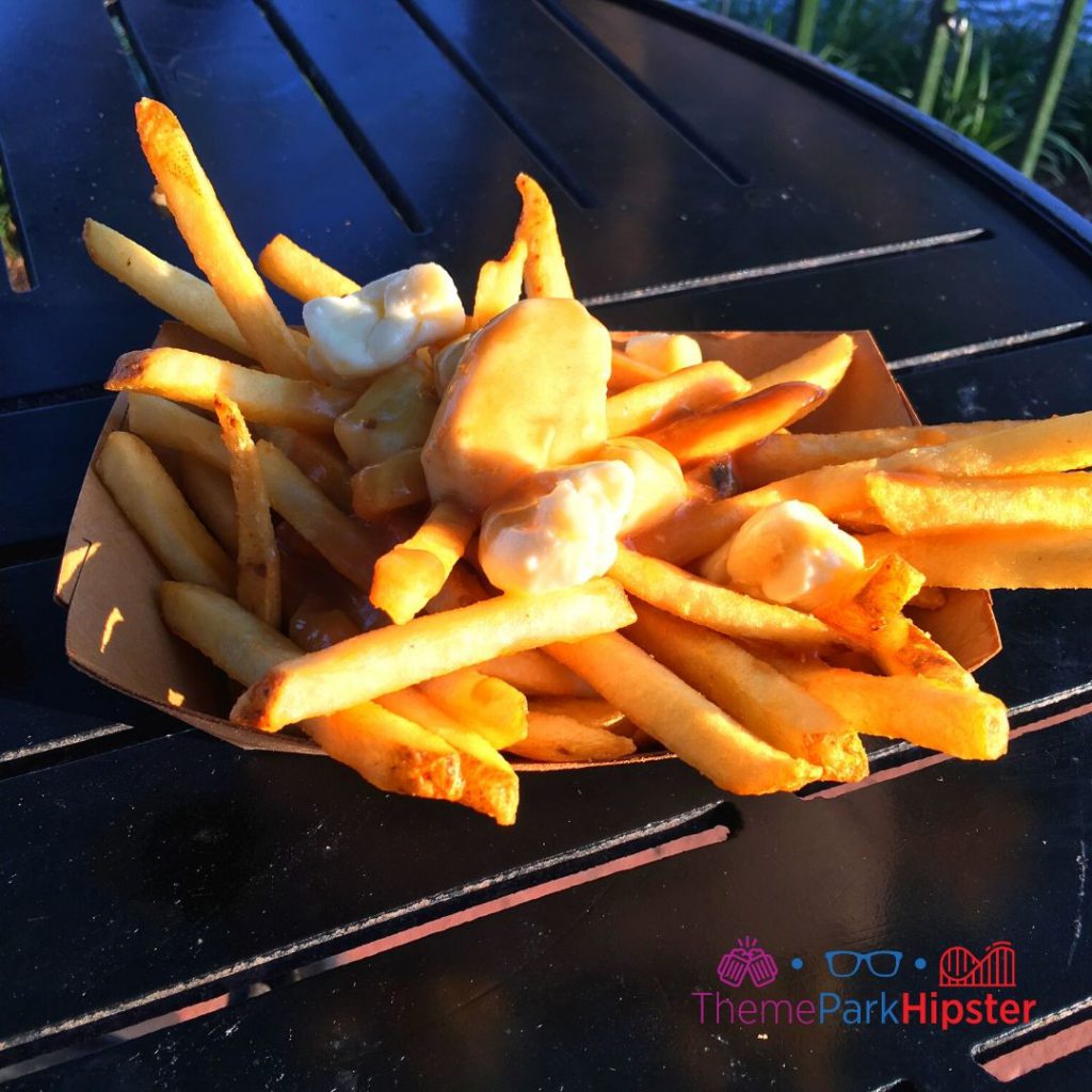 Canada Poutine with Fries Gravy and Cheese Curds on Black Table Available All Year. One of the best snacks at EPCOT. 