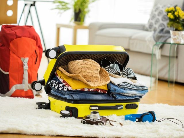 Packing for Disney World at Dollar Tree with over-sized yellow suitcase. Keep reading to know what to pack for an amusement park and have the best theme park packing list.