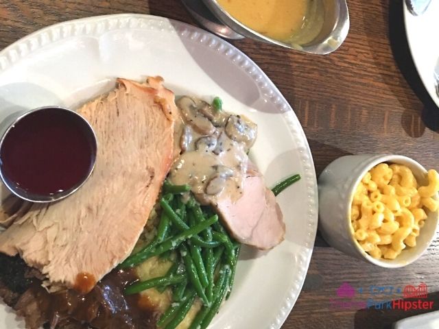 Liberty Tree Tavern Magic Kingdom Turkey Mashed Potatoes Gravy Mac and Cheese on white plate. Keep reading to learn how to do Thanksgiving Day dinner at Disney World.