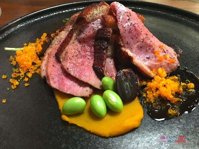 Takumi Tei Japanese Restaurant Epcot Kamo Rosu - Roasted Duck_ Marinated Duck, Kabocha Squash, Edamame Beans, Japanese Mizuna, Cured Duck Egg Yolk, Grape Reduction. Keep reading to learn about the top best fun things to do at Disney World for adults.