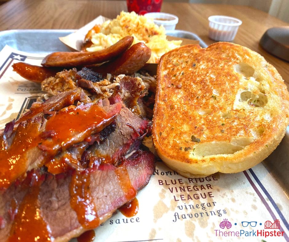 Regal Eagle Smokehouse at Epcot Beef Brisket covered in barbecue sauce with cream mac and cheese and buttery toast. One of the best quick service restaurants in Epcot!