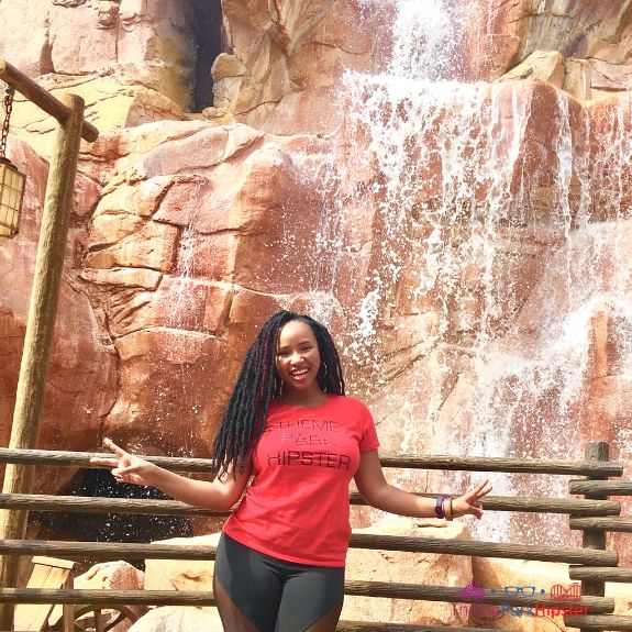 NikkyJ of ThemeParkHipster in Front of a cascading waterfall in Canada Pavilion at Epcot. 