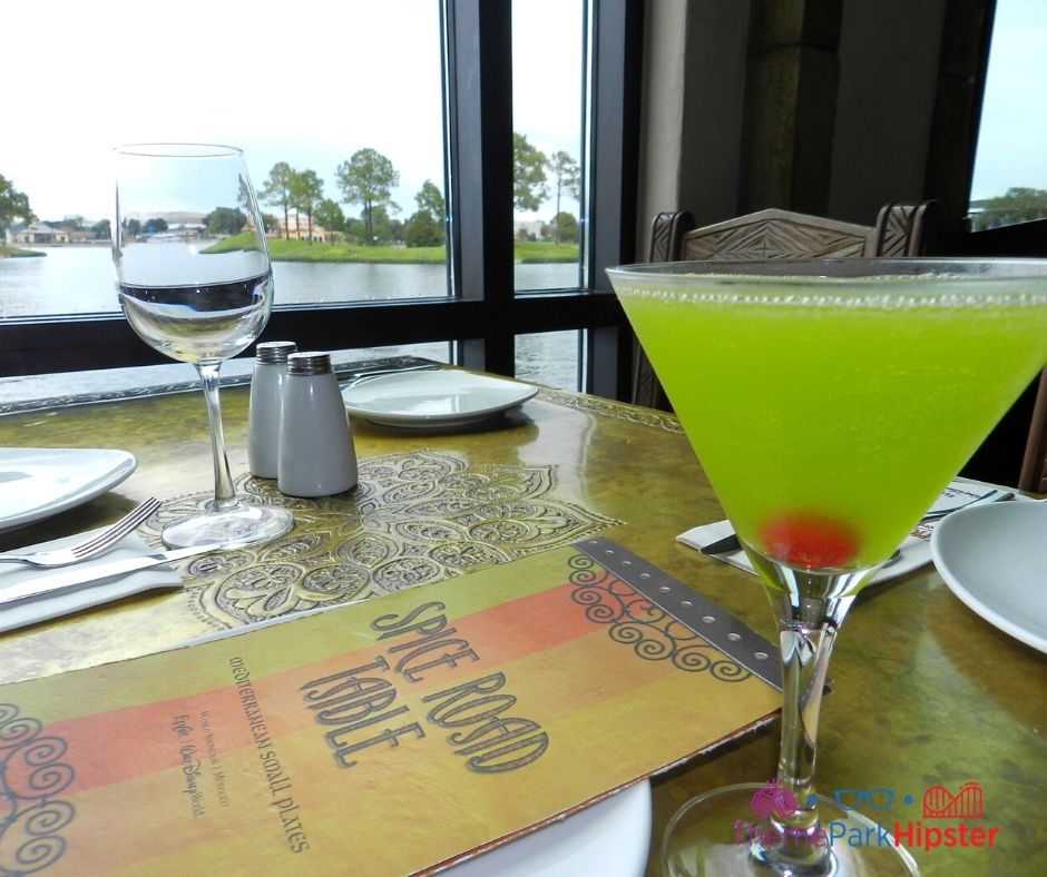 Spice Road Table at Epcot Green Martini over looking World Showcase Lagoon. Keep reading to learn about the best Disney park for adults.