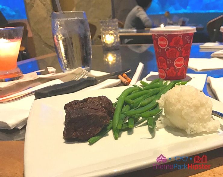 Living Seas restaurant at Epcot Rainbow prime steak with green beans and rice overlooking aquarium