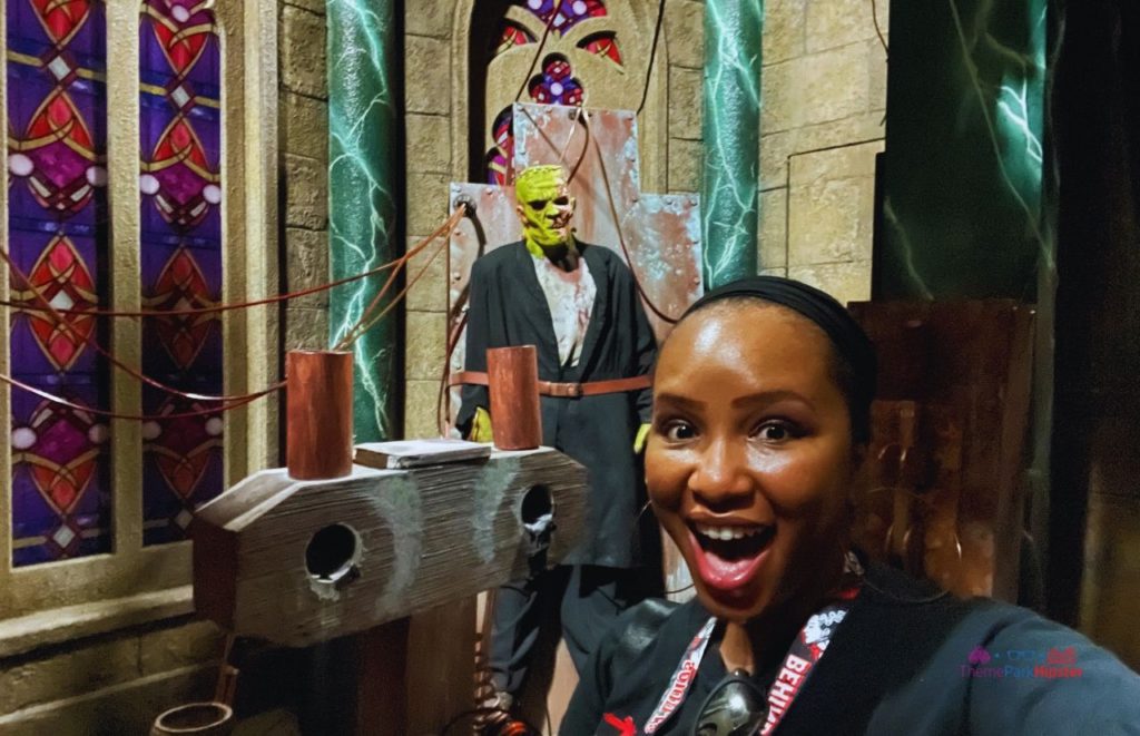 NikkyJ of ThemeParkHipster wearing a lanyard in front of a monster at Unmasking the horror tour Universal Monsters The Bride of Frankenstein Lives HHN 30. Keep reading if you want to learn more about Universal Studios outfit ideas. 