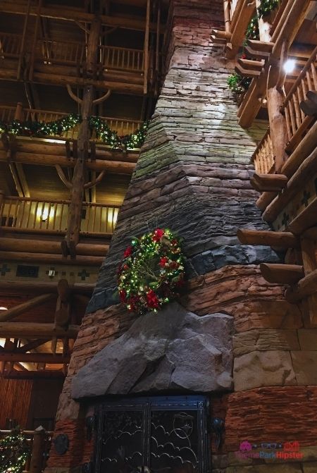 Disney Wilderness Lodge Large Fireplace with Christmas Reef on Top. Keep reading to get the full guide to Disney Wilderness Lodge Christmas activities.