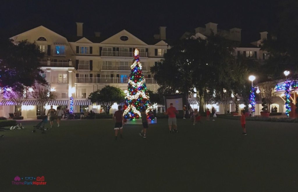Disney Yacht Club Christmas Tree Outside People Watching Movie on the Lawn. Keep reading to learn about the Disney World Gingerbread house display on Theme Park Hipster!
