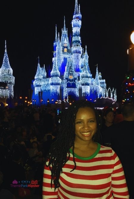 NikkyJ in front of sparkling Cinderella Castle at Christmas. Keep reading to know what to pack for an amusement park and have the best theme park packing list.