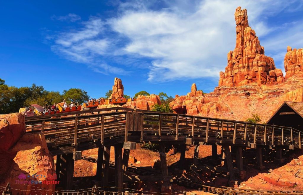 Disney Magic Kingdom Big Thunder Mountain Railroad roller coaster going over the bridge Frontierland. Keep reading to get get the best solo travel safety tips for your Disney World trip alone.