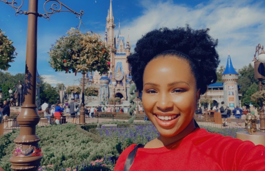 NikkyJ in front of Cinderella Castle at the Magic Kingdom. Keep reading to get get the best solo travel safety tips for your Disney World trip alone.