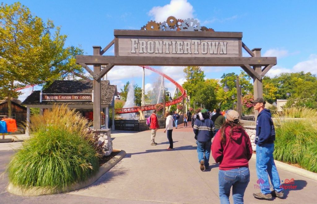 Guests walking to Maverick Roller Coaster by entering under the rustic and worn FrontierTown entryway sign at Cedar Point. Keep reading if you want to learn more about the history, theme, ride stats and fun facts about the Maverick at Cedar Point!