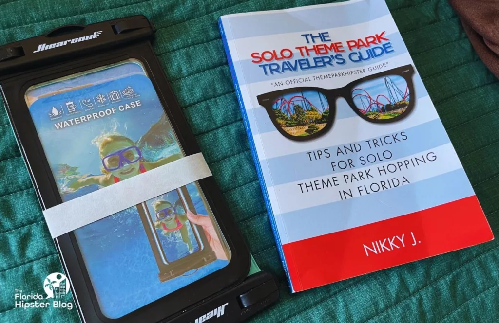 Waterproof Phone Case next to The Solo Theme Park Traveler's Guide by NikkyJ. Keep reading to get the best Universal Studios packing list and what to pack for Universal Orlando Resort.