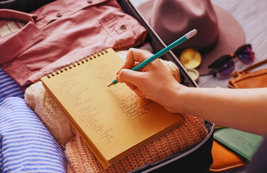 Lady writing with pencil while working on theme park packing list. Keep reading to get the best Universal Studios packing list and what to pack for Universal Orlando Resort.