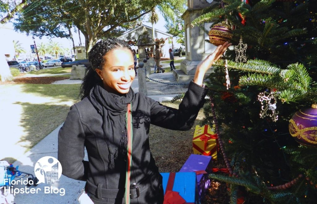 NikkyJ holding ornaments on Christmas tree in St Augustine Florida. One of the best day trips from Orlando for solo travelers.