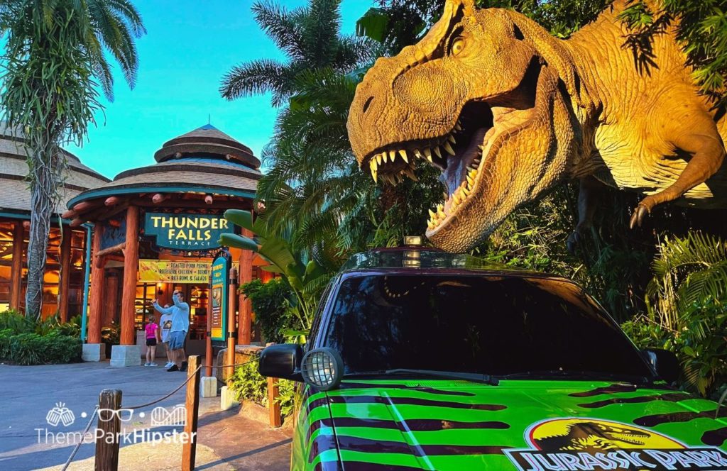 Jurassic Park River Adventure with Tyrannosaurs above green jeep next to Thunder Falls Universal Orlando Resort Islands of Adventure. Keep reading to learn more about Hulk vs VelociCoaster at Universal Orlando Resort.
