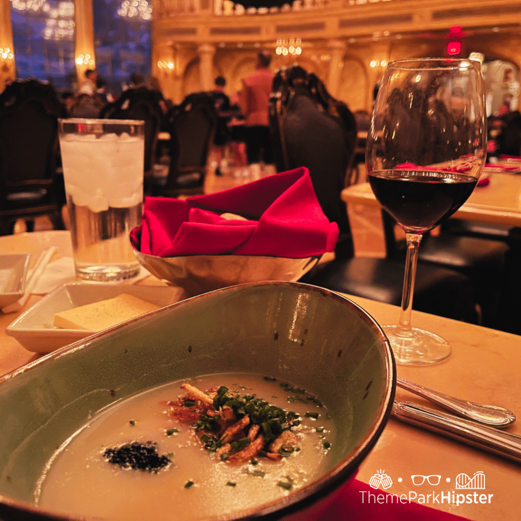 Beast Castle Potato Soup at  Be Our Guest Restaurant with a glass of wine. Keep reading to find out more of the best things to do at Disney World on a solo trip.