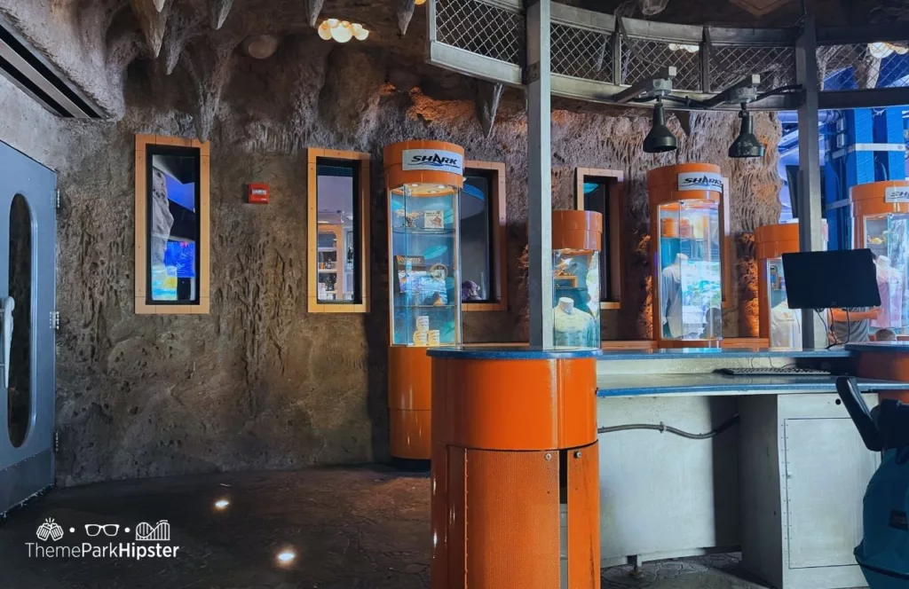SeaWorld Orlando Resort Sharks Underwater Grill check in area with orange display cabinets of photos and merchandise. Keep reading to find out more about Sharks Underwater Grill at SeaWorld Orlando.