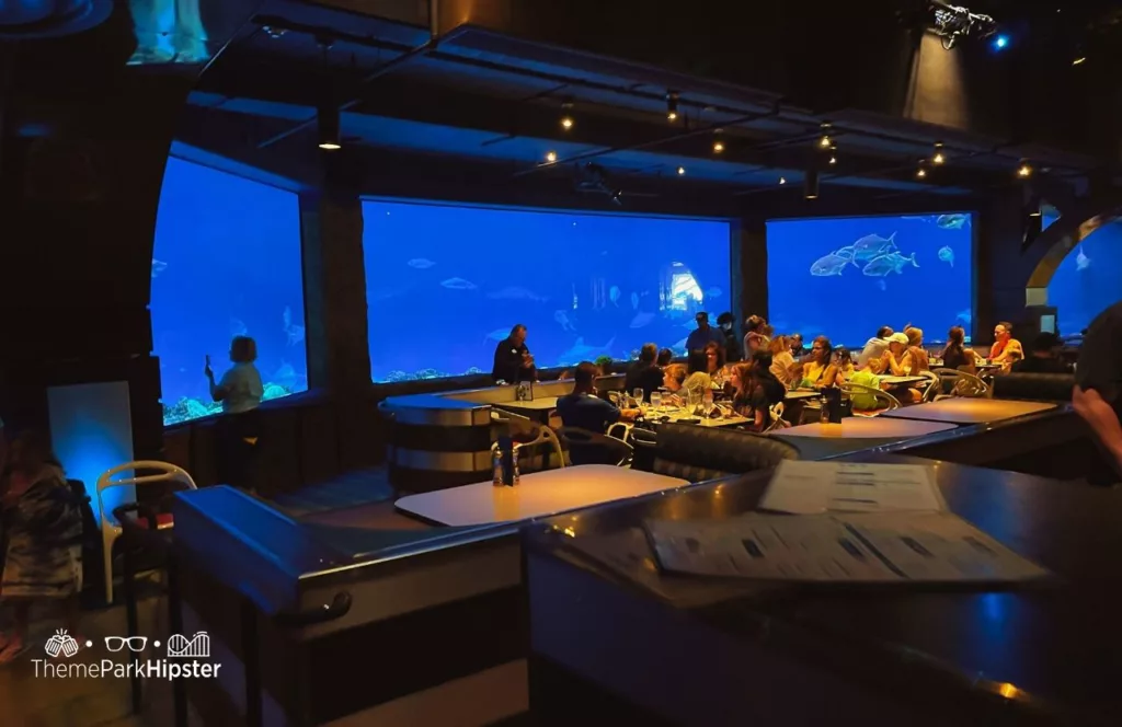 SeaWorld Orlando Resort Sharks Underwater Grill interior with floor to ceiling views into the shark tank. Keep reading to discover more about Sharks Underwater Grill at SeaWorld Orlando.