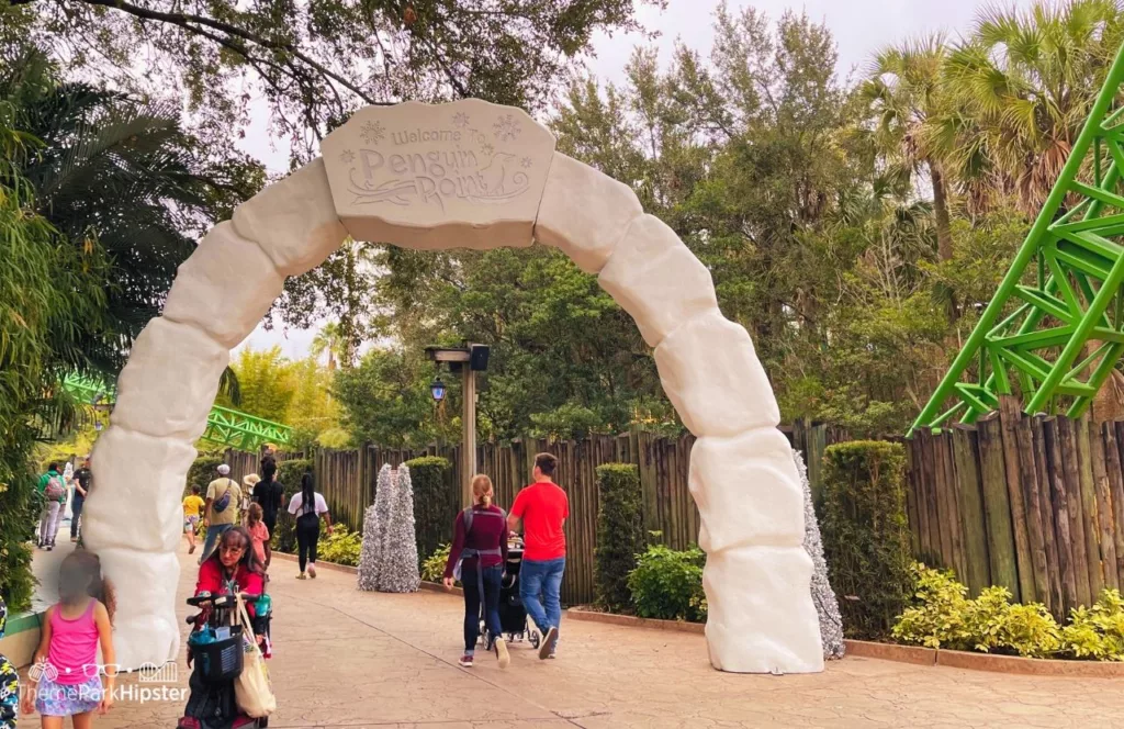 Penguin Point igloo shaped arch at Busch Gardens Tampa Bay with theme park visitors and families walking underneath. Keep reading to learn about Busch Gardens Tampa animals. 