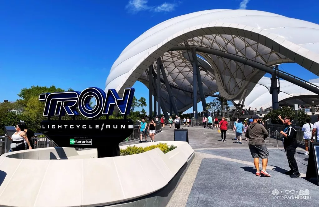 Entrance to Tron Lightcycle Run at the Magic Kingdom in Walt Disney World Resort Florida Tomorrowland with theme park enthusiasts walking around, Keep reading to learn more about Universal Orlando Coasters: Hulk vs VelociCoaster.