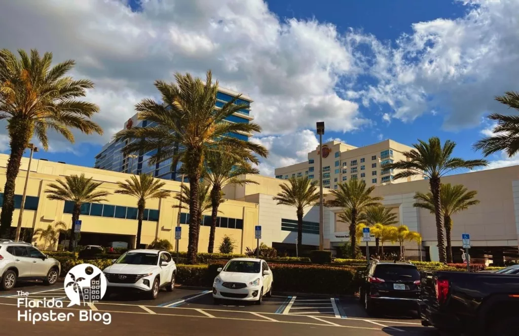 Seminole Hard Rock Hotel Casino Parking Lot with cars and tropical trees under the Florida sunshine and white fluffy clouds. Keep reading to learn more about the best hotels near Busch Gardens Tampa.