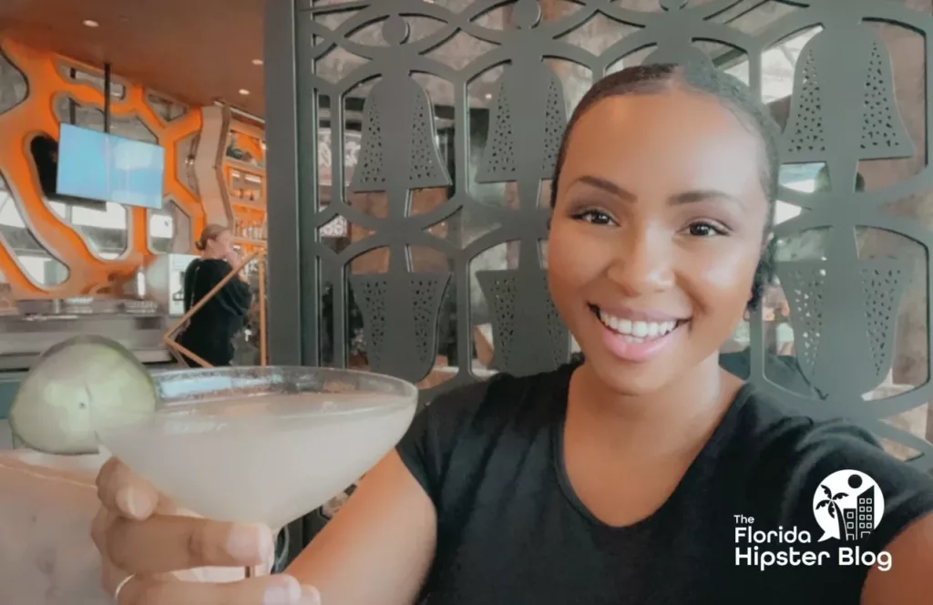 NikkyJ at Disney's Dahlia Lounge at Coronado Springs Resort, holding a beverage. Keep reading to find out the most romantic things to do at Disney World.