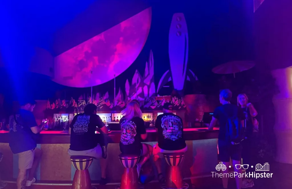 Guests sitting at the bar with eerie lighting during 2023 Halloween Horror Nights HHN 32 at Universal Studios. Keep reading to discover more about Halloween at Universal. 
