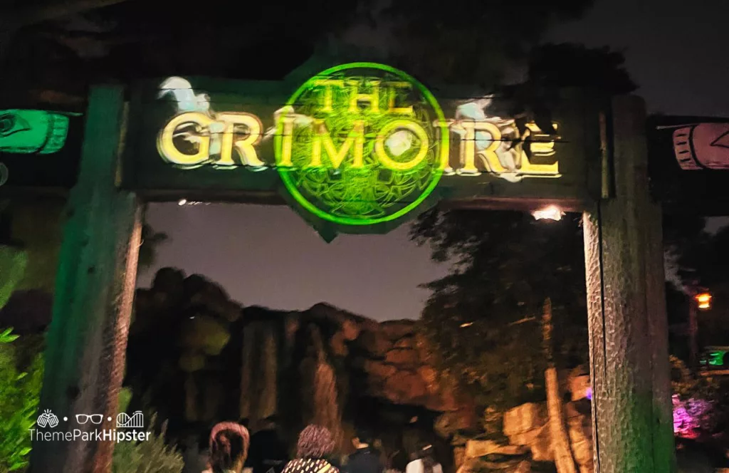 The Grimoire House entrance glowing in green and yellow with theme park guests walking through the entrance to the haunted house at Knott's Scary Farm in California. Keep reading to learn more about Knott’s Scary Farm houses.