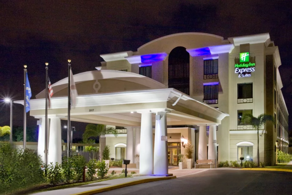 Holiday Inn Express and Suites with a grand covered drive thru front entrance at Busch Gardens Tampa, lit up with blue glowing lights on the exterior. Keep reading to learn more about the best hotels near Busch Gardens Tampa.
