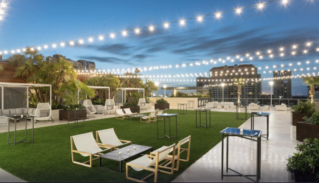 JW Marriott Tampa Water Street rooftop area with plenty of greenery, table, and seating areas spread all across for privacy and twinkle lights hanging above overlooking Tampa. Keep reading to discover what are the best hotels near Busch Gardens Tampa.