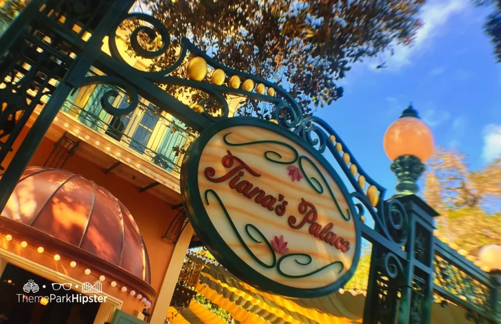 2024 Princess and the Frog, Tiana's Palace Restaurant sign under the balcony at Disneyland. Keep reading to find out more about Tiana’s Palace Disneyland.
