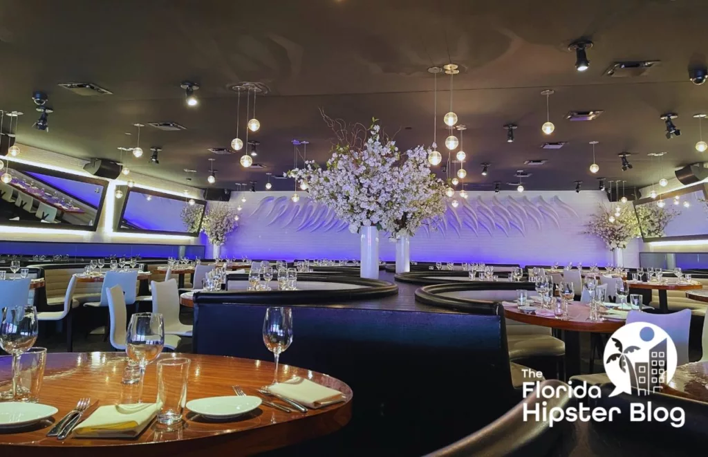 STK Orlando interior with chic and elegant table settings, hanging lights and grand, tall floral arrangements. Keep reading to find out all you need to know about STK Disney Springs.