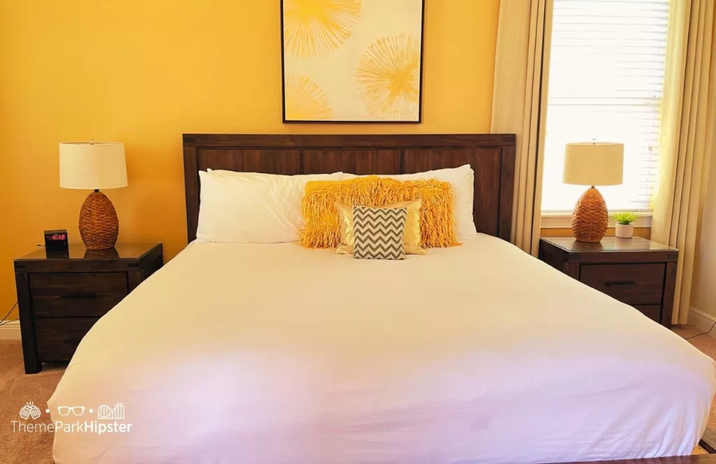 5 Bedroom Villa at Encore Resort of large bed with white bedding and yellow accents and side tables. Keep reading to learn more about Encore Resort Orlando.
