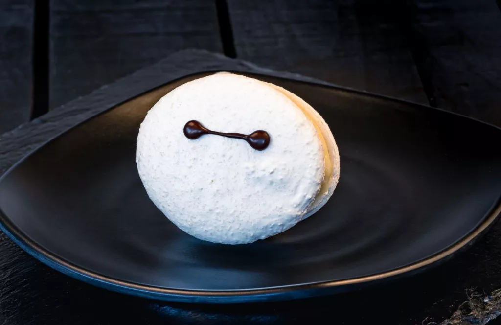 Baymax Macaron (Lucky Fortune Cookery) filled with chocolate-hazelnut spread and buttercream. Keep reading to learn more about the best things to eat at Disneyland. 
