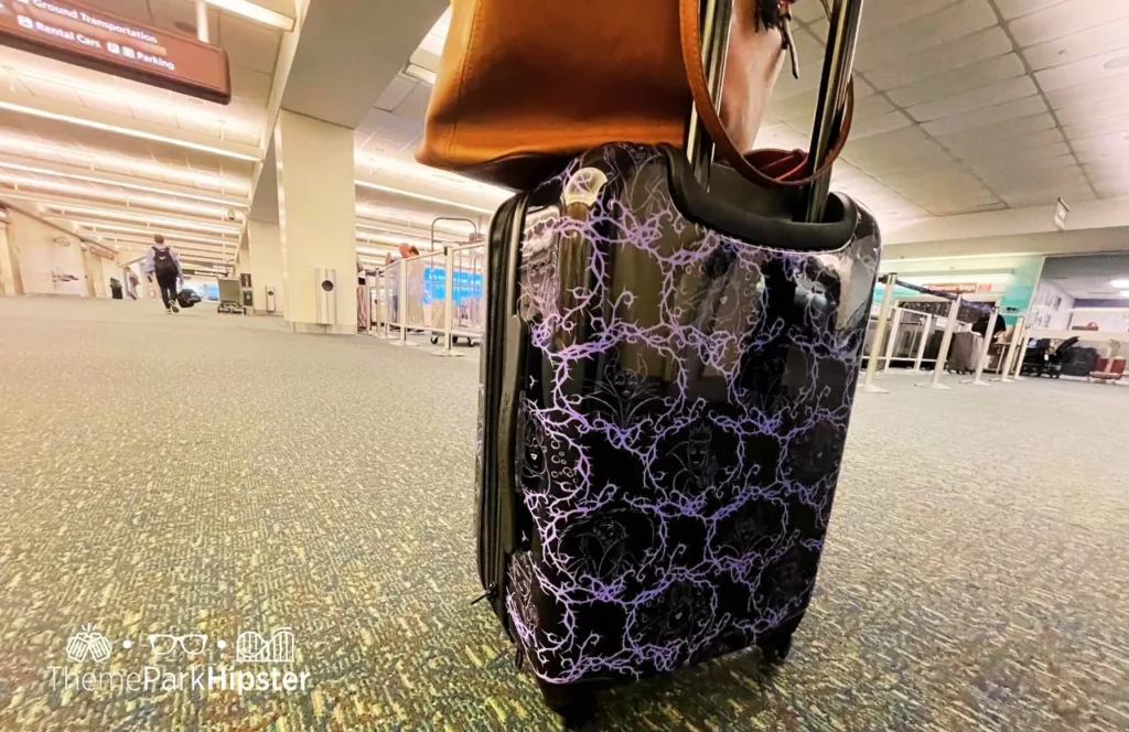 Disney Villains Purple and Black suitcase in the airport. One of the best luggage for Disney World