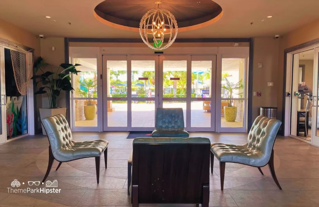 Lobby area with hanging chandelier light, chic sitting area and automatic sliding glass doors. Keep reading to find out more about Encore Resort Orlando.