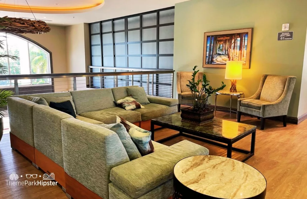 Lounge area and bar with large wrap around sofa seating and chairs with tables and ambient lighting and wide windows. Keep reading to hear more about Encore Resort Orlando. 