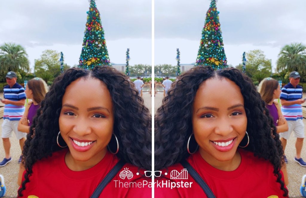 NikkyJ in front of Christmas tree at SeaWorld Orlando Christmas Celebration. Keep reading to see why you should do solo travels to theme parks!
