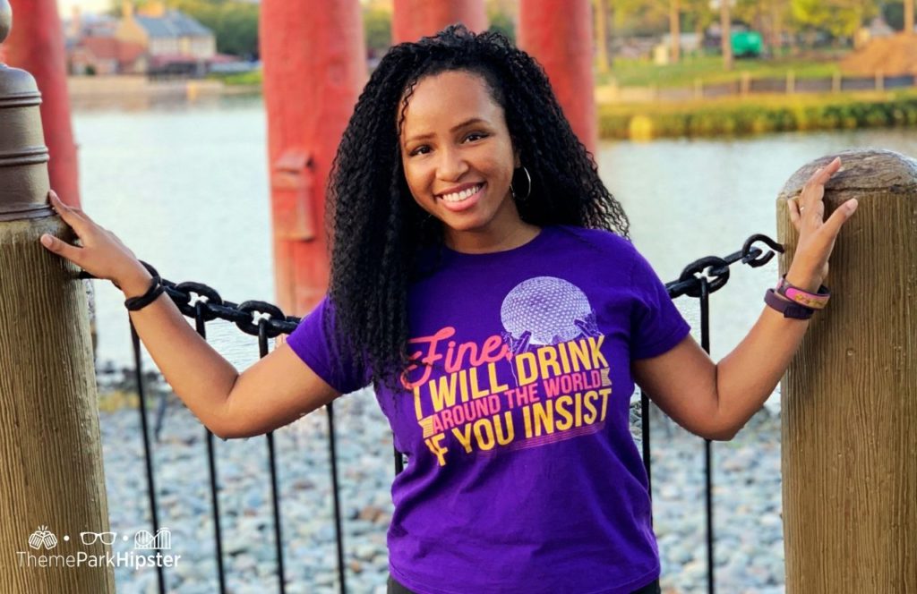 Walt Disney World Epcot World Showcase with NikkyJ in her Fine I Will Drink Around the World If You Insist t shirt. Keep reading to discover more about how much it costs to park at Disney World.
